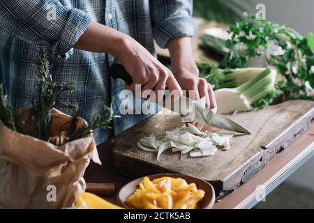 Mittelteil des jungen Mannes, der Fenchel an Bord in der Küche schneidet Stockfoto