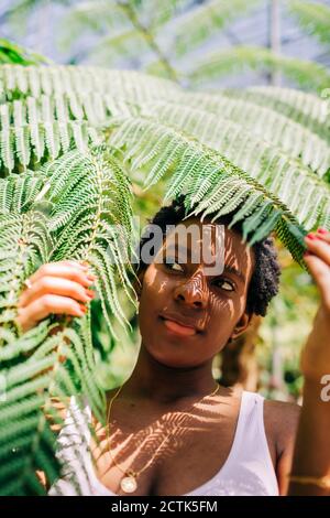 Schöne Frau versteckt sich hinter Blättern im Park Stockfoto