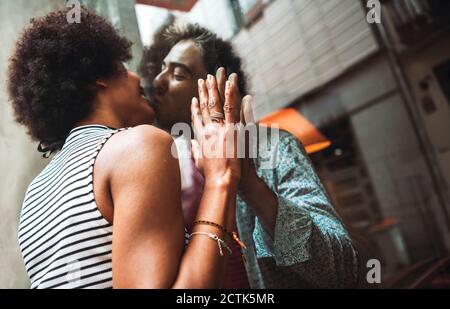 Romantische Frau küssen Freund durch Fenster des Cafés, während Im Freien stehen Stockfoto