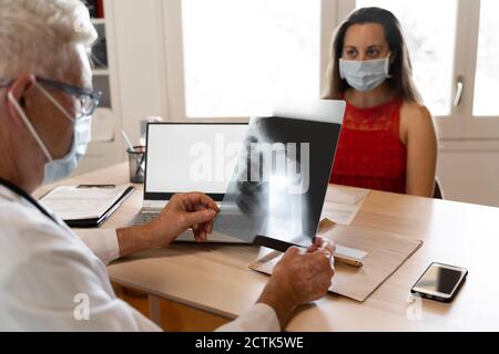 Der Arzt schaut sich die medizinische Röntgenaufnahme des menschlichen Halses an, während er sitzt In der Klinik Stockfoto