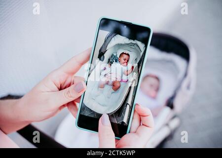 Mutter, die ein Foto mit Handy von Baby Mädchen Im Kinderwagen Stockfoto