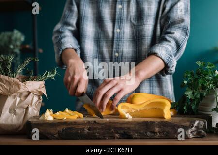 Hände von Mann schneiden gelben Paprika an Bord in Küche Stockfoto