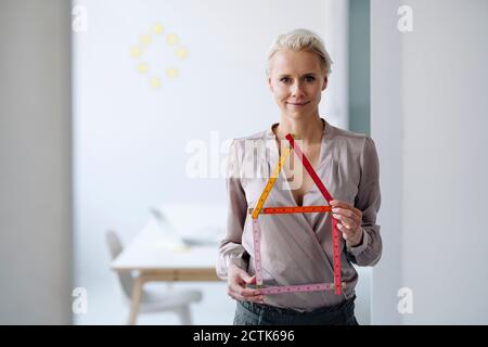 Selbstbewusste weibliche Unternehmerin hält Modell, während im Büro stehen Stockfoto