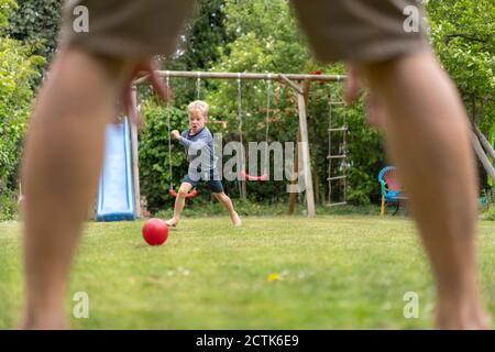 Junge spielt Fußball mit Vater im Hinterhof am Wochenende Stockfoto