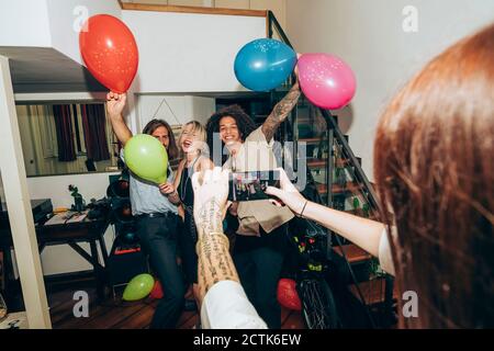 Frau fotografiert Freunde tanzen während der Party zu Hause Stockfoto
