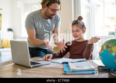 Lächelnder Vater lehrt Tochter zu Hause Stockfoto