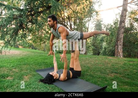 Männliche und weibliche Athleten üben acroyoga im öffentlichen Park Stockfoto