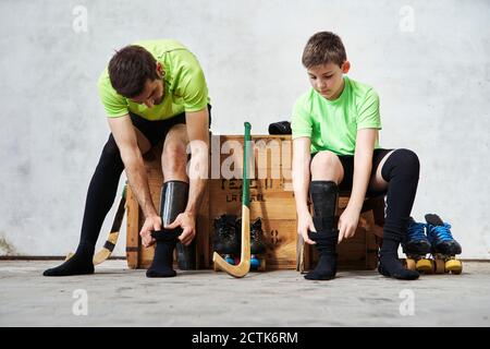 Vater und Sohn tragen Socken, während sie auf einer Holzkiste sitzen Vor Gericht Stockfoto