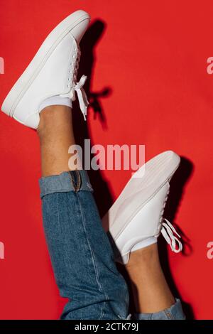 Nahaufnahme einer Frau in Sneakers mit den Füßen auf Rot Hintergrund Stockfoto