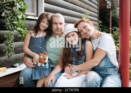 Glückliche Familie sitzt auf der Veranda des Hauses Stockfoto