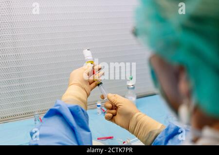 Nahaufnahme einer Apothekerin, die Fläschchen und Spritze im Labor hält Stockfoto