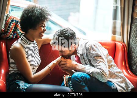 Romantischer Mann küsst sich auf die Hand der Freundin, während er im Kaffee sitzt Kaufen Stockfoto