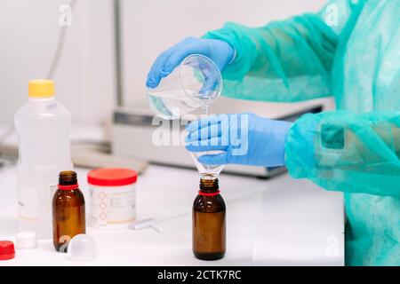 Nahaufnahme einer Wissenschaftlerin, die im Labor Flüssigkeit in die Flasche gießt Stockfoto