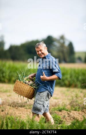 Mann zeigt Daumen nach oben beim Gehen auf der Farm Stockfoto