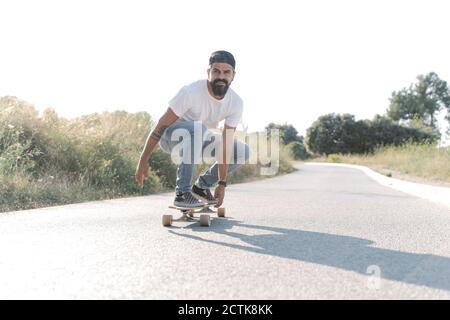 Schöner Mann Skateboarding auf der Straße gegen klaren Himmel Stockfoto