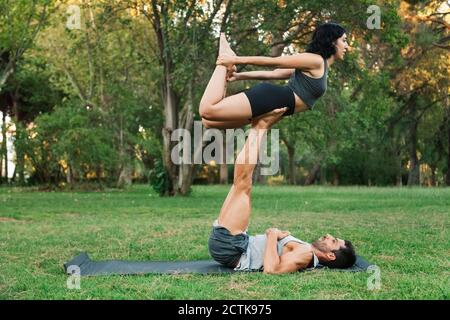 Mann Balancing Freundin auf Beinen während dabei acroyoga im Park Stockfoto