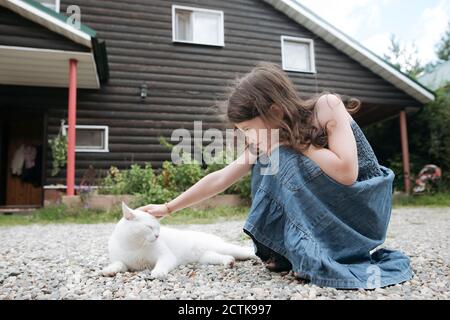 Kleines Mädchen streichelte Katze im Vorgarten des Hauses Stockfoto