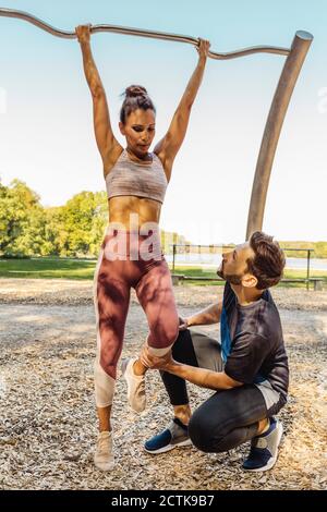 Mann, der die Frau unterstützt, hebt sich auf einem Fitnessparcours Stockfoto