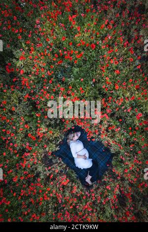 Schwangere mittlere Erwachsene Frau schlafen auf Decke in Mohnfeld Stockfoto