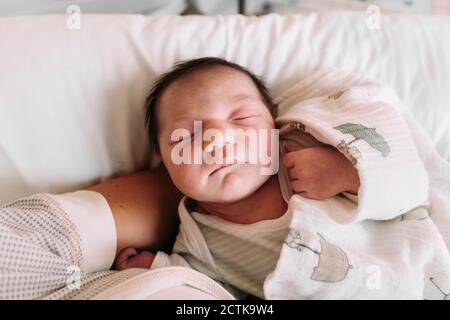 Nahaufnahme des neugeborenen Mädchens, das auf dem Arm der Mutter schläft Krankenhaus Stockfoto