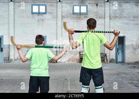 Vater und Sohn in Uniform halten Hockeyschläger beim Sport gericht Stockfoto