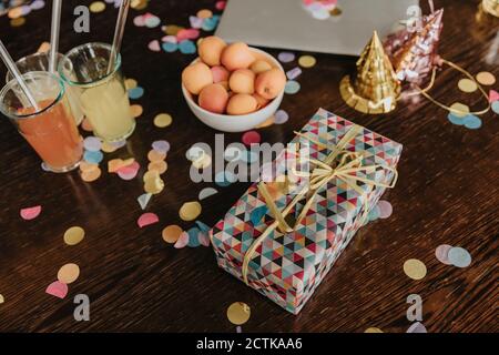 Geburtstagsgeschenk mit Getränken und Aprikosen auf unordentlichen Esstisch Zu Hause Stockfoto