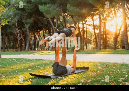 Männliche und weibliche Athleten üben acroyoga im Park während des Sonnenuntergangs Stockfoto