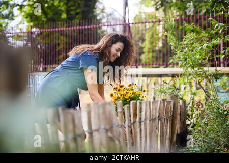 Lächelnde Frau mit Blumen im Garten Stockfoto