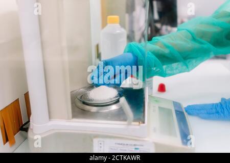 Hände von Wissenschaftlerin Messung Pulver Medizin auf Skala in Labor Stockfoto