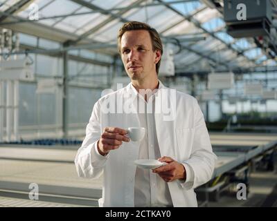 Wissenschaftler mit einer Kaffeepause in einem Gewächshaus Stockfoto
