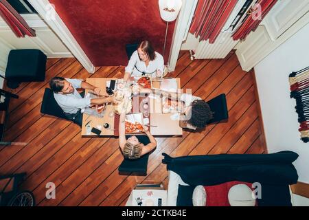 Freunde toasten Weingläser, während sie Pizza während der Party zu Hause haben Stockfoto