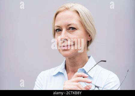 Nahaufnahme einer Geschäftsfrau, die im Büro eine Brille an die Wand hält Stockfoto