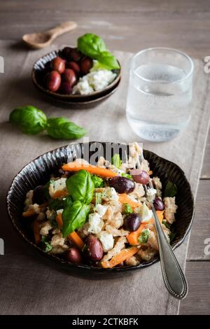 Schüssel mit vegetarischen Spätzle mit Karotten, Oliven, Feta-Käse und Basilikum Stockfoto