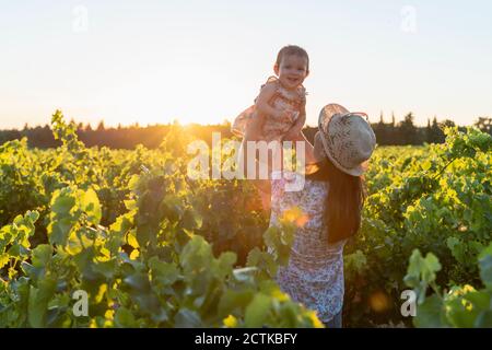 Mutter hält ihre Tochter in einem Weinberg bei Sonnenuntergang in der Provence, Frankreich Stockfoto