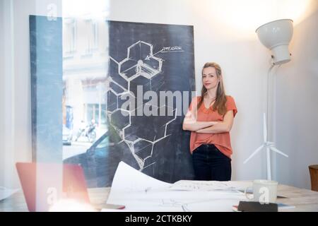 Selbstbewusste Frau steht an der Tafel mit Zeichnung im Büro Stockfoto