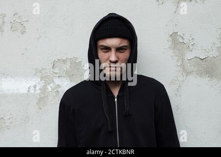 Mann mit Hoodie, der gegen die Wand steht Stockfoto