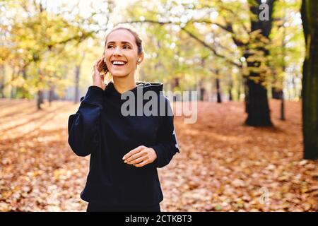 Junge Joggerin mit Ohrhörern im Herbstwald Stockfoto