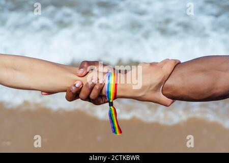 Nahaufnahme eines Paares, das an einem sonnigen Tag die Hände über dem Meer hält Stockfoto