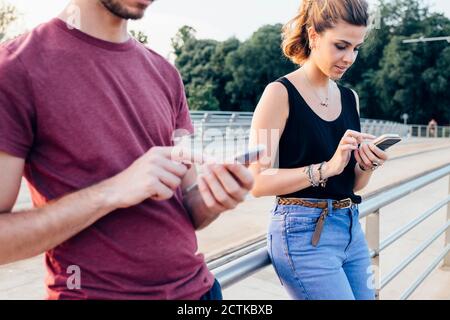 Paar mit Smart Phones beim Stehen auf Brücke Stockfoto