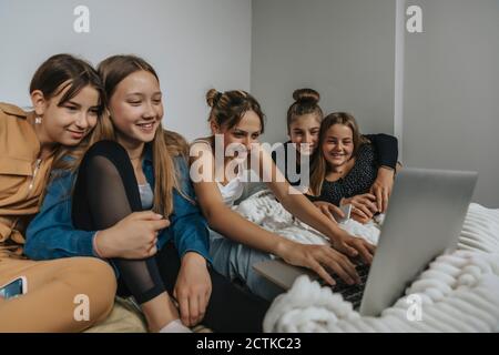 Gruppe von Freundinnen sitzen auf dem Bett, Film auf Laptop Stockfoto