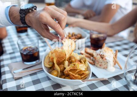 Zugeschnittenes Bild des Mannes, der Kartoffelchip im Café hat Stockfoto