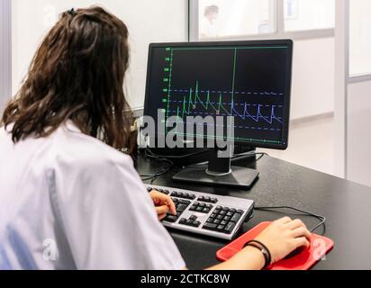 Ärztin analysiert Liniendiagramm über Computer im Krankenhaus Stockfoto Ärztin analysiert Liniendiagramm über Computer im Krankenhaus Stockfoto