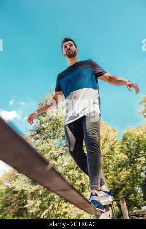 Mann balanciert auf Slackline auf einem Fitness-Parcours Stockfoto