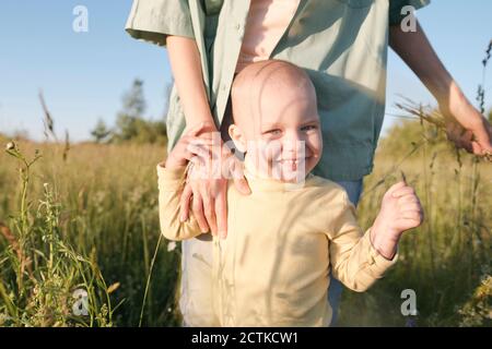 Glücklicher Junge steht mit Mutter auf dem Feld während sonnigen Tag Stockfoto