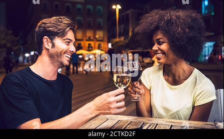 Fröhliches Paar, das sich ansieht, während sie Weingläser anrösten Datum Nacht Stockfoto