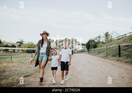 Mutter mit Tochter und Sohn, die auf dem Weg gegen den Himmel gehen Stockfoto