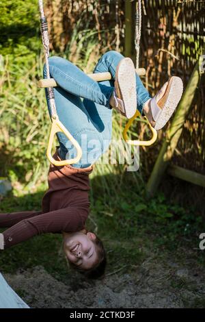 Mädchen hängen kopfüber auf der Stange im Hinterhof Stockfoto