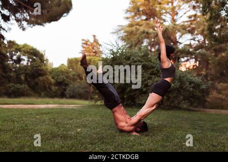 Männliche und weibliche Athleten üben acroyoga im Park Stockfoto