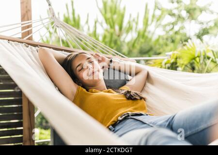 Schöne Frau mit den Armen, die auf der Hängematte im Hof ragen Stockfoto