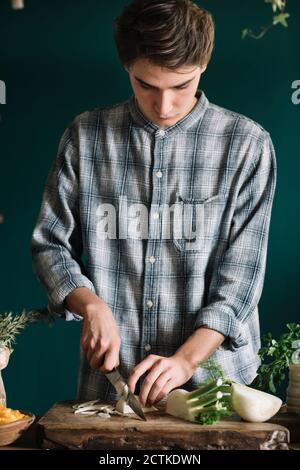 Hübscher junger Mann, der Fenchel an Bord in der Küche schneidet Zu Hause Stockfoto